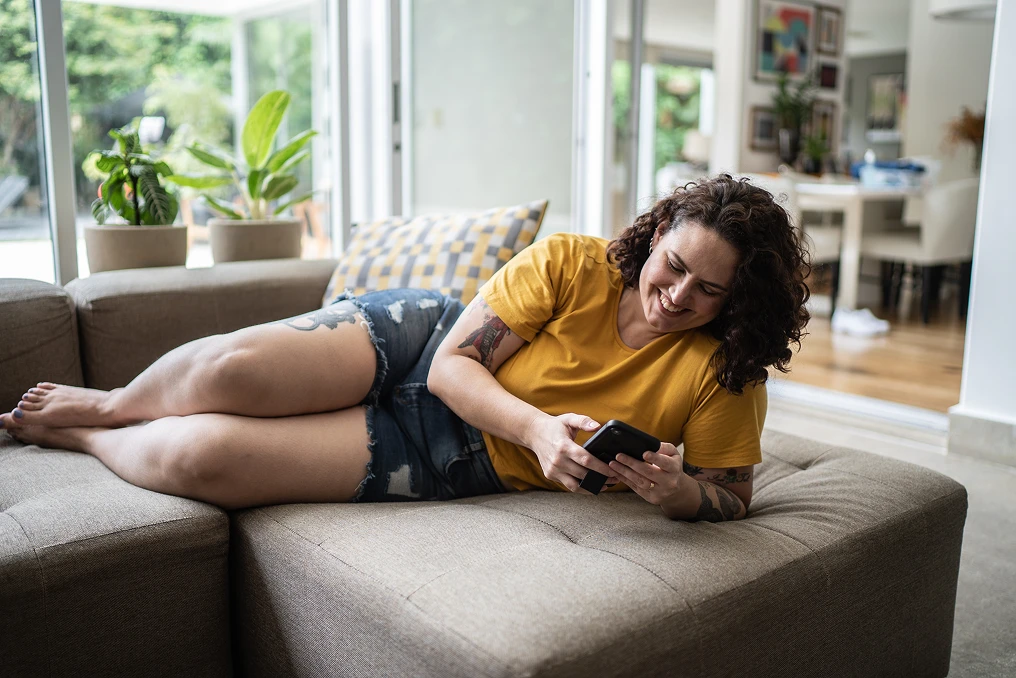 Mulher deitada no sofá usando celular
